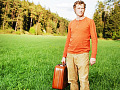 man standing alone holding a suitcase
